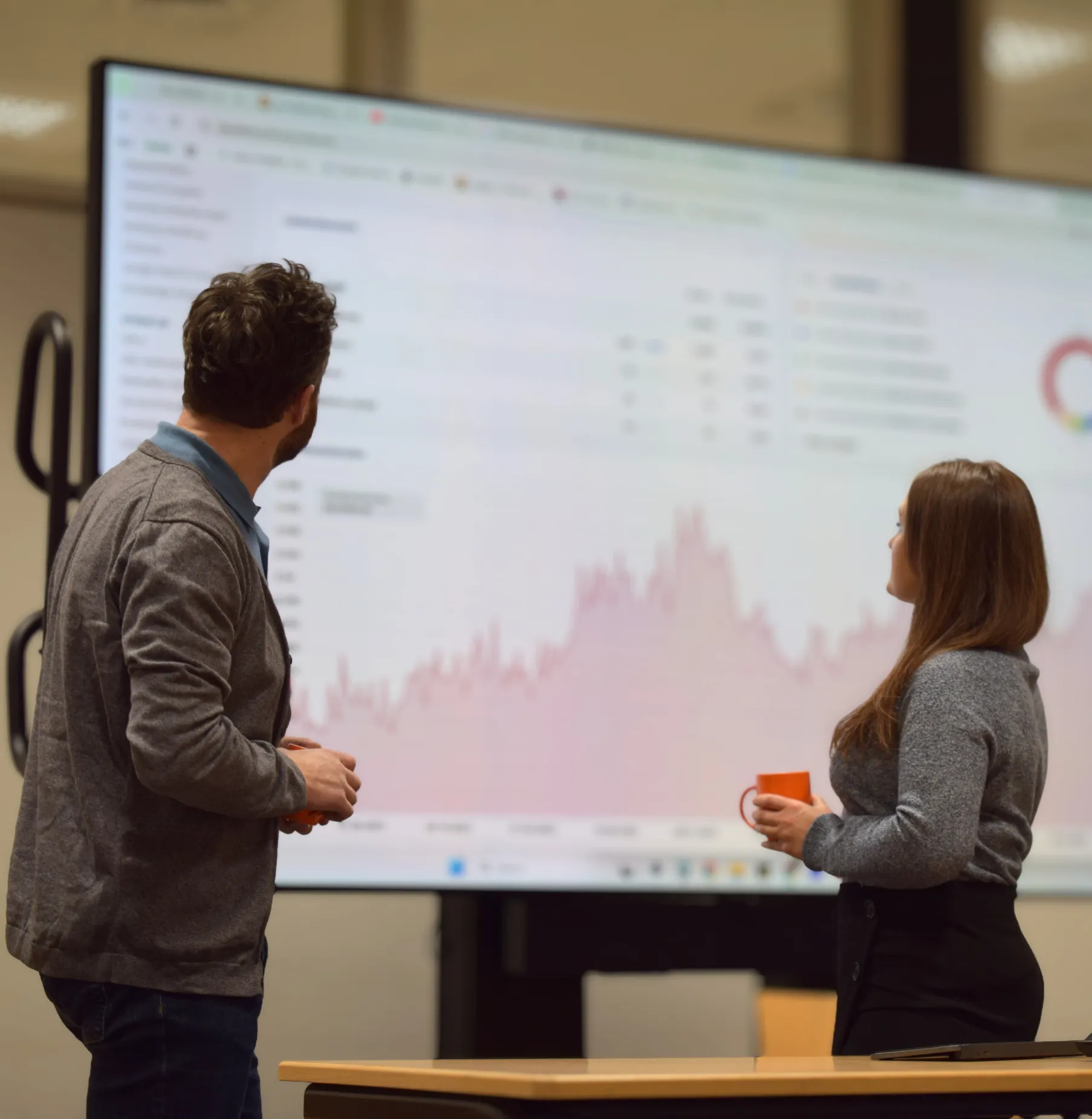 Website Relaunch Agentur Berater bei der gemeinsamen Analyse der Daten und Planung der neuen Seitenstruktur vor einem großen Monitor.